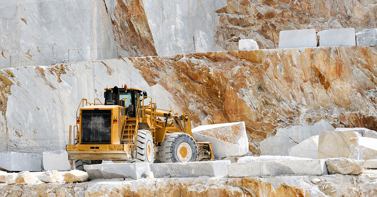 Heavy machinery extracting white Thassos marble blocks from a historic quarry, showcasing the centuries-old tradition of Thassos marble production in Greece.